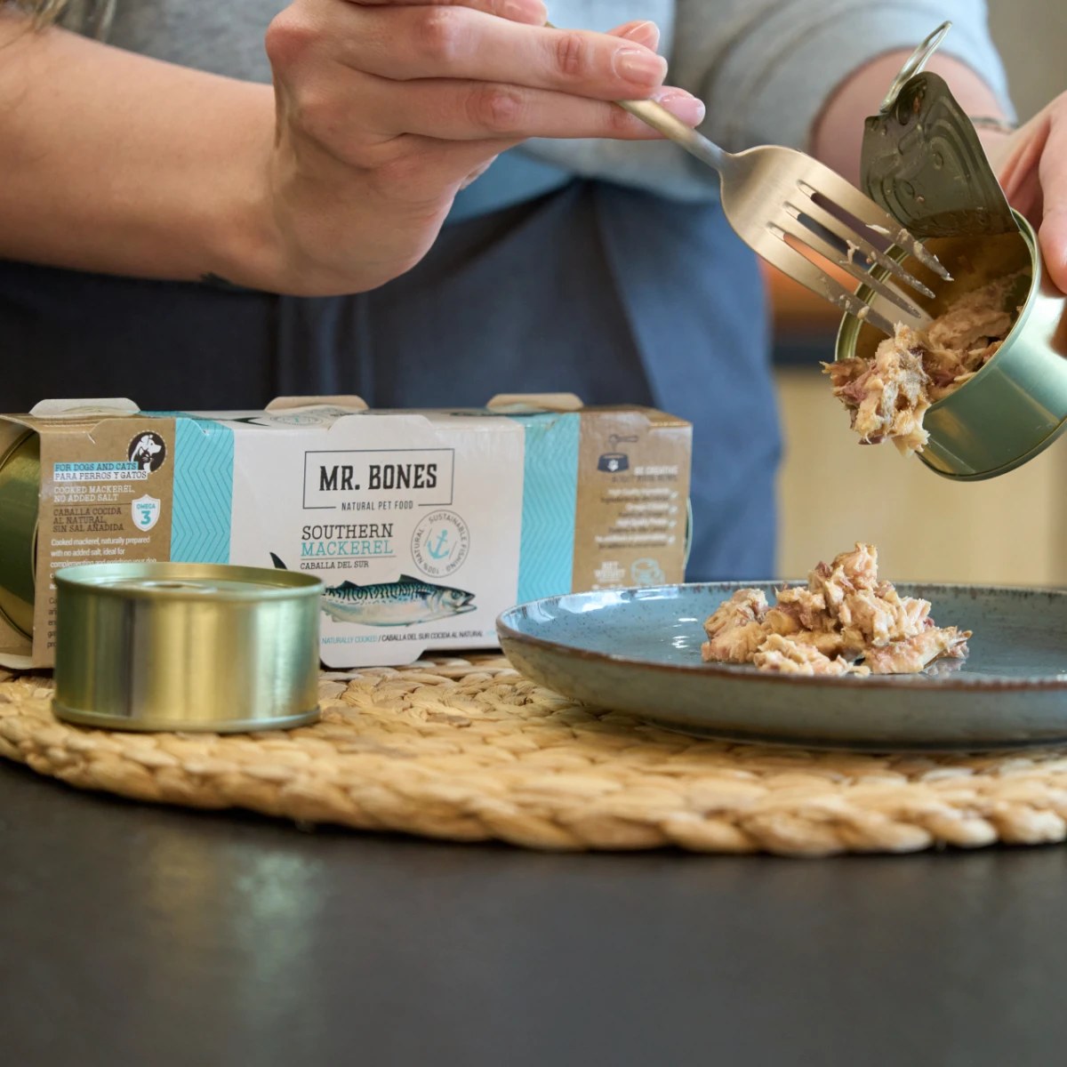 Hand tar makrill ur öppnad burk med gaffel