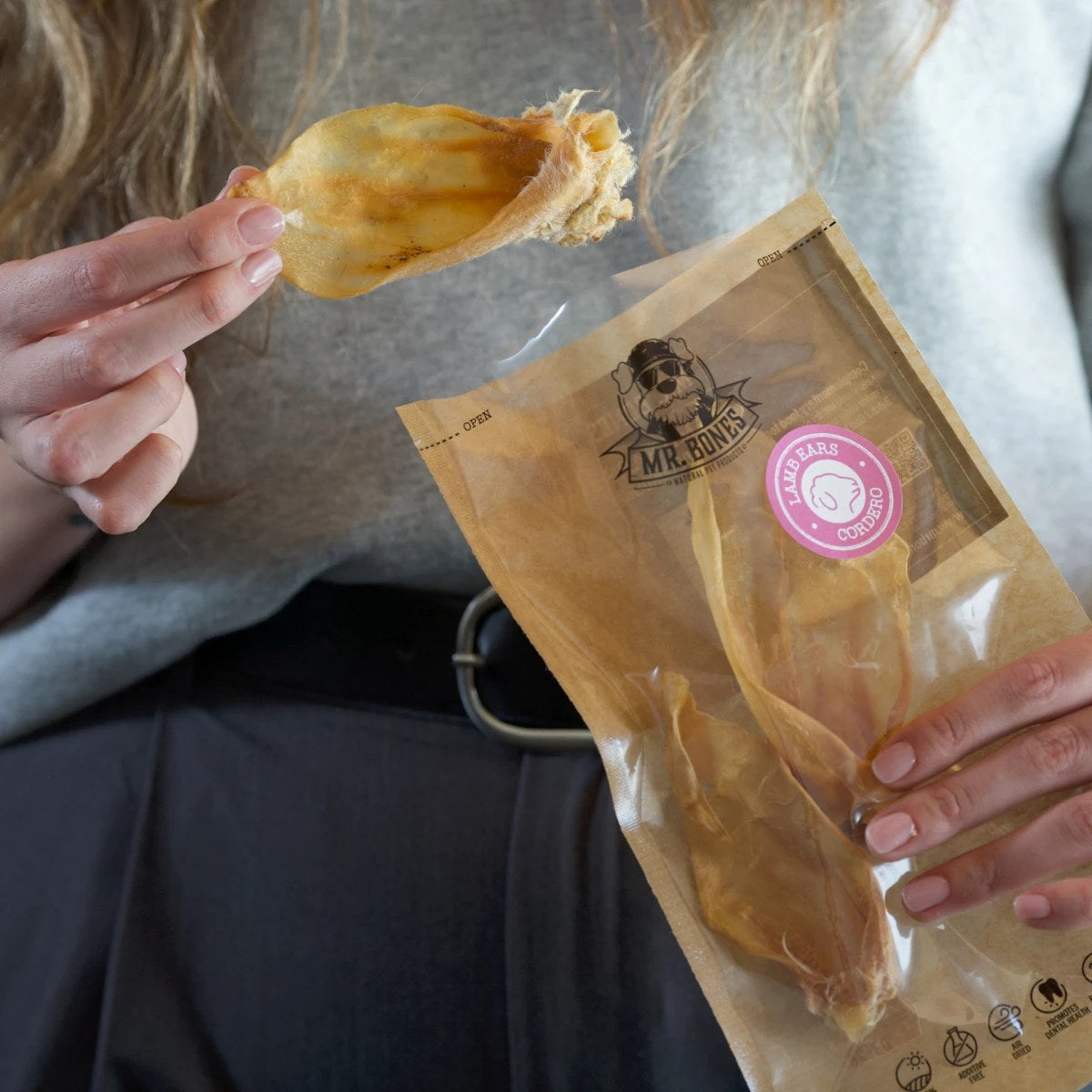 Hand håller ett torkat lammöra framför påsen