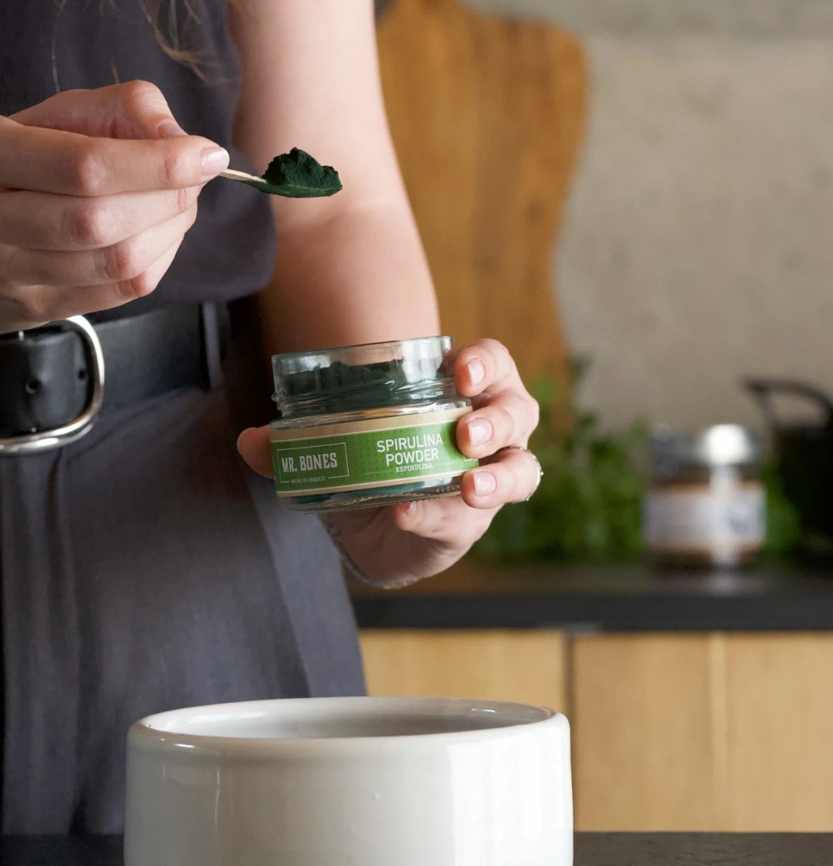 Sked med spirulinapulver ströas över hundmat