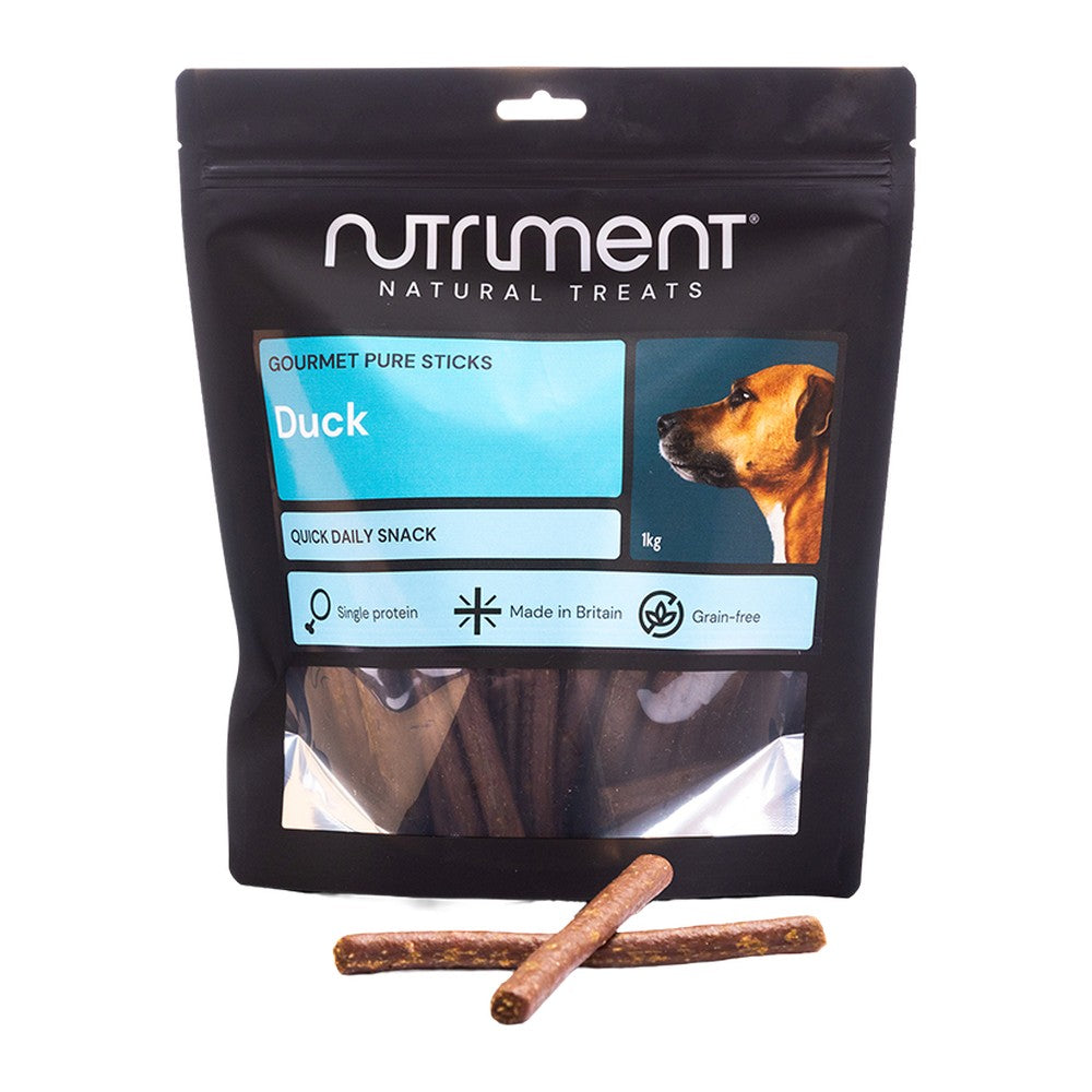 Nutriment Gourmet Pure Sticks Anka 1kg, stor svart påse med ljusblå etikett och godispinnar framför, mot vit bakgrund