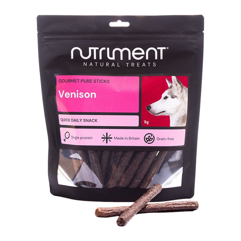 Nutriment Gourmet Pure Sticks Hjort 1kg, stor svart påse med rosa etikett och godispinnar framför, mot vit bakgrund